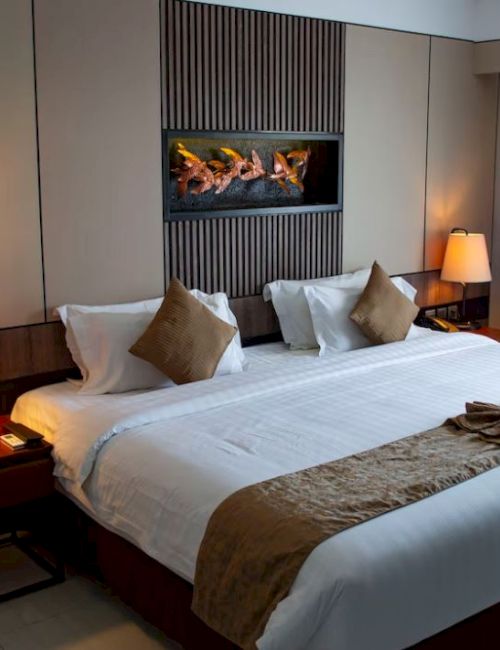 A cozy hotel room featuring a large bed, bedside tables with lamps, a wall-mounted artwork above the headboard, and a window with closed curtains.