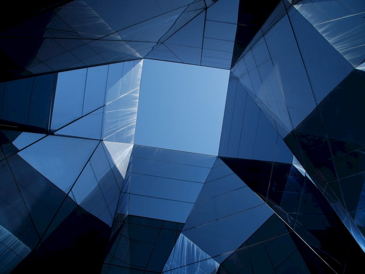 This image shows a geometric pattern formed by the reflections on mirrored surfaces, with a view of the blue sky at the center.