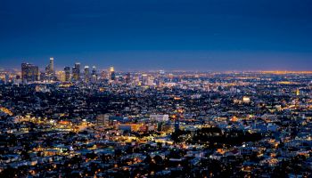 The image shows a sprawling cityscape at night with skyscrapers in the distance and a multitude of lights glowing throughout the urban area.