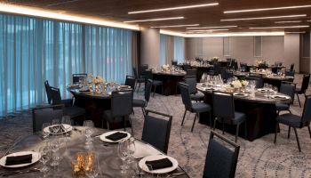 A decorated banquet hall with round tables and chairs set up for an event, featuring elegant table settings and ambient lighting.